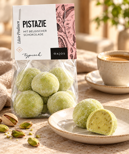 Pistazienlikör-Pralinen mit Anschnitt und Pistazien zu Espresso im hellen Café-Ambiente